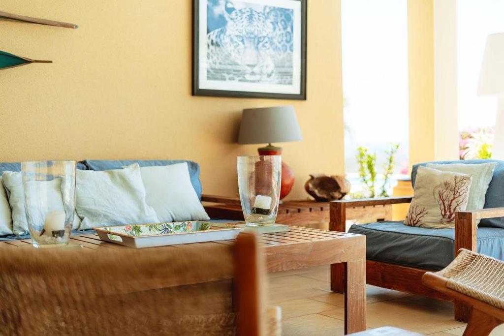Véranda de Villa Lakaz avec canapés bleus, fauteuils en bois et vue sur la mer