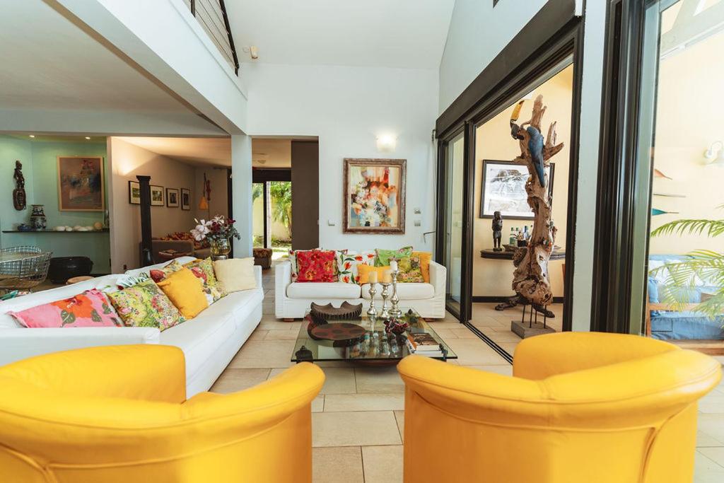 Grand salon de Villa Lakaz, canapés blancs, fauteuils jaunes et grandes baies vitrées