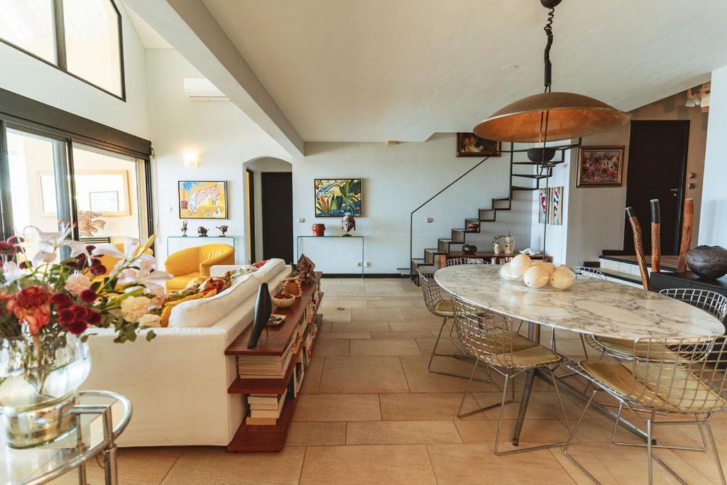 Grand salon de Villa Lakaz avec canapé blanc, fauteuils jaunes et escalier hélicoïdal
